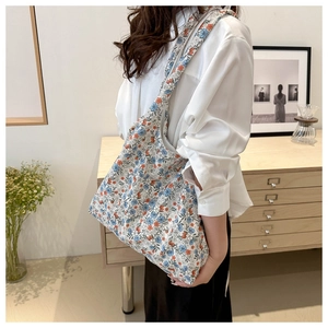 Floral canvas tote bag with wide shoulder strap shown in a cozy home setting