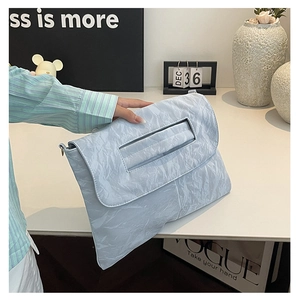 Détail d'une pochette bleu clair à texture froissée avec anneaux métalliques sur le côté
