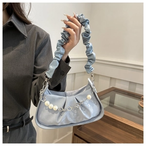 Close-up of light blue pleated underarm bag with pearl flower chain and ruffled strap