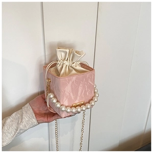 Detail of pink bucket bag with pleated texture, pearl handle, and drawstring closure