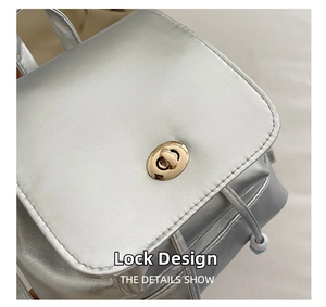 Detail of silver metallic backpack featuring a gold oval twist-lock and drawstring closure