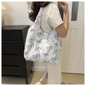 Detailed view of white faux fur tote bag with blue butterfly patterns on a model