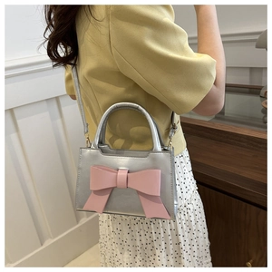 Detail of silver handbag with a large pink bow, styled with an elegant polka dot skirt
