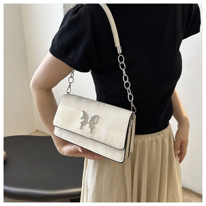 Detail of cream shoulder bag featuring silver butterfly buckle and marble texture