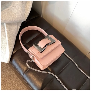 Macro detail of pink mini crossbody bag with oversized silver buckle and chain strap