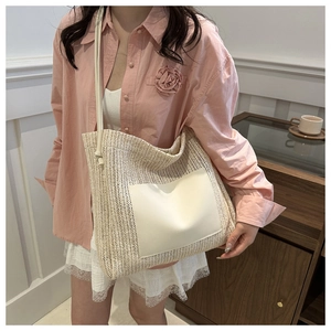 Close-up of a woven straw tote bag featuring a white faux leather front pocket detail