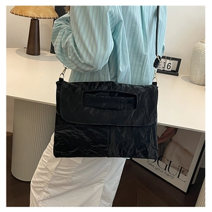 Close-up of black pleated PU leather crossbody bag with unique hollow handle design