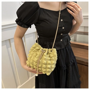 Detail of pleated bubble texture bucket bag with gold chain and large pearl drawstring