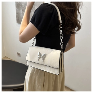 Detail of pearlescent beige crossbody bag with silver butterfly buckle and chain strap