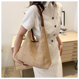 Detail view of woven straw shoulder bag with brown leather straps on model shoulder