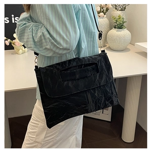 Detail view of black pleated nylon shoulder bag with golden metal hooks and thin strap
