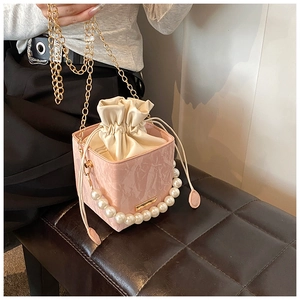 Detail of pink marble textured box bag with large pearl handle and gold chain strap
