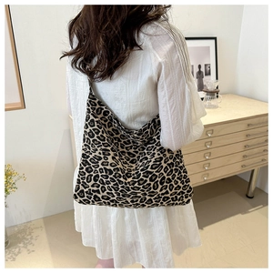 Rear view of a model carrying a large leopard print canvas tote bag in a stylish room