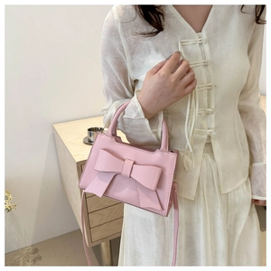 Detail of pink bow handbag featuring premium PU leather and top handle in lifestyle setting
