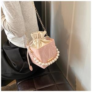 Detail of pink marble pattern bucket bag featuring a pearl handle and gold chain strap