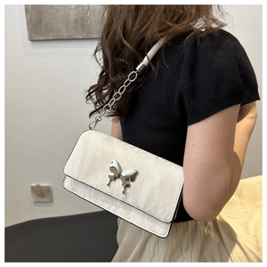 Detail of cream crossbody bag featuring marble texture and silver butterfly buckle