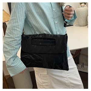Detail of black pleated PU leather crossbody bag with metallic sheen and gold hardware