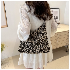 Leopard print hobo shoulder bag worn by model in a cozy, minimalist interior setting
