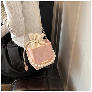 Detail of pink bucket bag with pearl handle, gold chain and drawstring closure