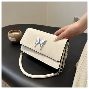 Detail of cream quilted bag with silver butterfly buckle and stylish chain strap