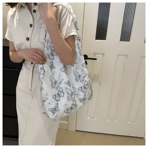Close-up of high-capacity white tote bag with realistic blue butterfly print on a model