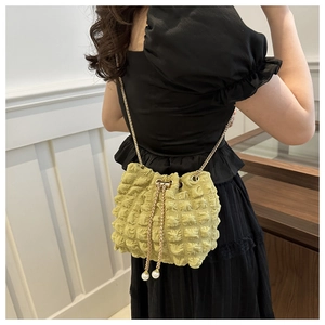 Detail of green bubble texture bucket bag with pearl drawstring and gold chain