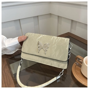 Detail of light green crossbody bag featuring a silver butterfly buckle and chain strap