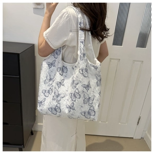 Detailed back view of a large fuzzy tote bag featuring blue butterfly prints and soft texture