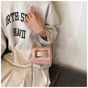 Detail of pink mini chain bag featuring a large silver square buckle and glossy finish