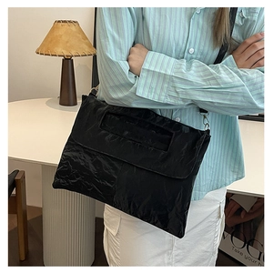 Détail du sac à bandoulière en nylon plissé noir avec boucle dorée et texture gaufrée