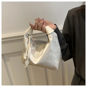 Gros plan d'un sac à main en satin avec broderie florale et cordon de serrage blanc