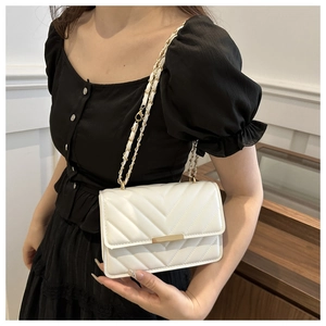 Detail der weißen Umhängetasche mit Chevron-Steppmuster und eleganter goldener Kette