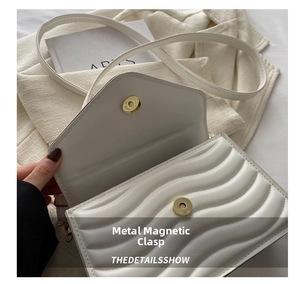 Detail of white quilted crossbody bag with premium golden magnetic hardware closure