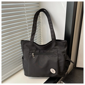 Detail of black canvas tote bag featuring front zipper pocket and good luck circular logo