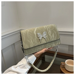 Detailed view of sage green quilted crossbody bag with silver butterfly charm decoration