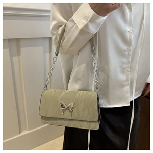 Detail of sage green wrinkled leather shoulder bag with silver butterfly buckle on a model