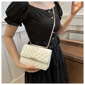 Detail einer weißen gesteppten Umhängetasche mit goldener Kette, von Model gehalten