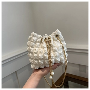Dettaglio borsa a secchiello bianca plissettata con catena dorata e coulisse con perle