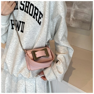Detail of pink mini crossbody bag featuring a large silver buckle and chain strap