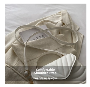 Detail of white quilted crossbody bag with adjustable strap on elegant blazer background