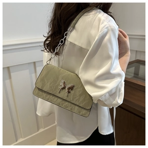 Detail of light green shoulder bag with silver butterfly ornament and pleated texture