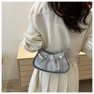 Detail of light blue pleated cloud bag with pearl and floral metal chain accessory