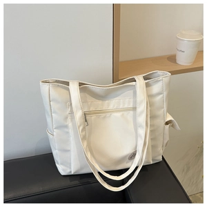 Detail of off-white tote bag with front zipper pocket and round badge on leather base