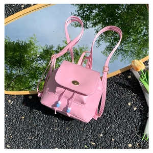 Detail of pink mini backpack with glossy PU finish, metal twist lock, and bead drawstring