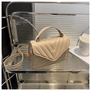 Detail of beige quilted PU leather crossbody bag with top handle and gold hardware chain