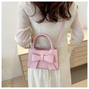 Close-up of pink fashion handbag with bow decoration and slim shoulder strap