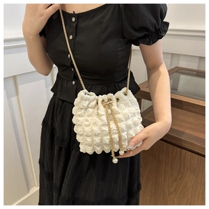 Dettaglio borsa a secchiello bianca texture popcorn con perle e catena d'oro