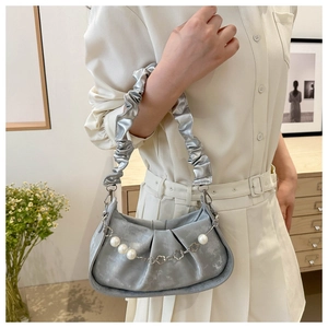 Close-up of a metallic silver crossbody bag with pearl chain and scrunchie handle detail