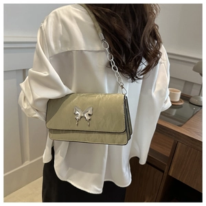 Detail of light green pleated crossbody bag with silver butterfly buckle and chain strap