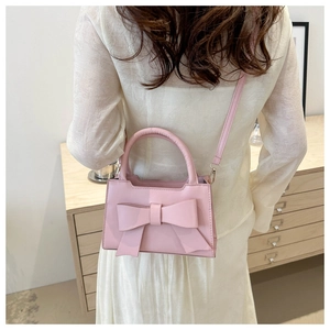 Pink bow handbag and crossbody bag styled with a white dress in a cozy setting